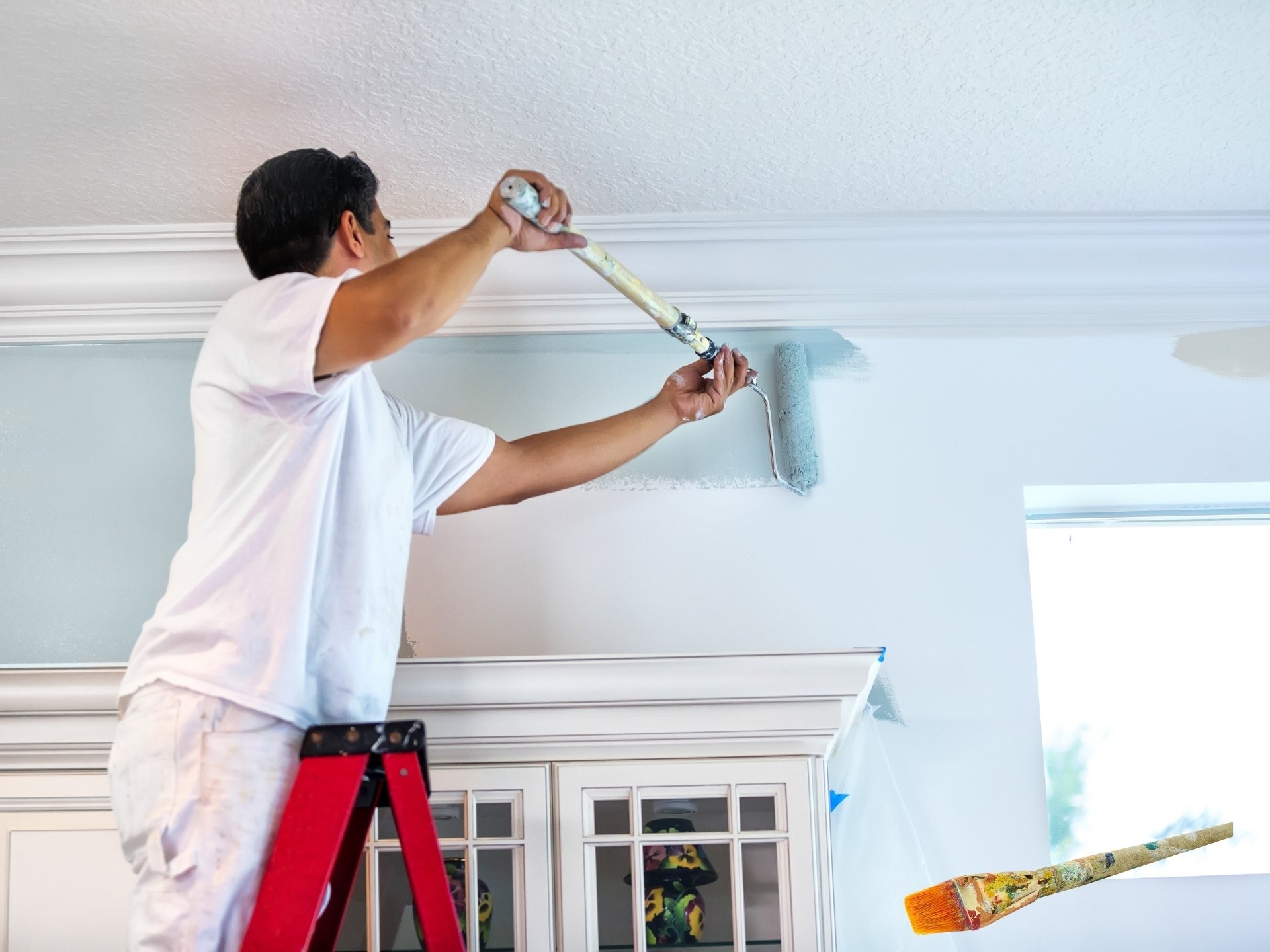 Interior House Painters: How to Choose the Right Experts for a Perfect Finish 1 Interior house painter on a ladder applying blue paint to a living room wall with precision and care.