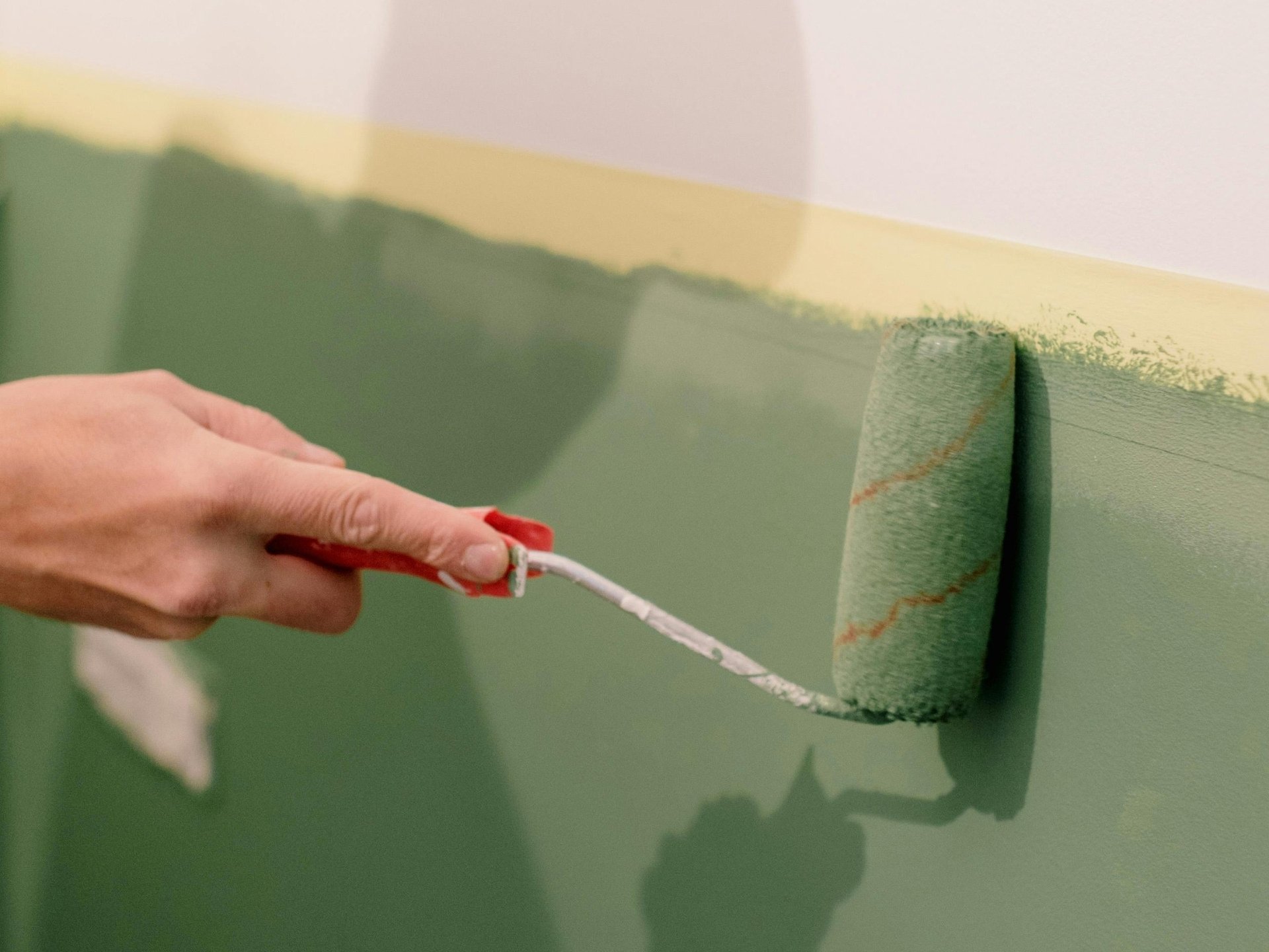 Interior House Painters: How to Choose the Right Experts for a Perfect Finish 2 Interior house painter applying green wall paint with roller for even satin finish